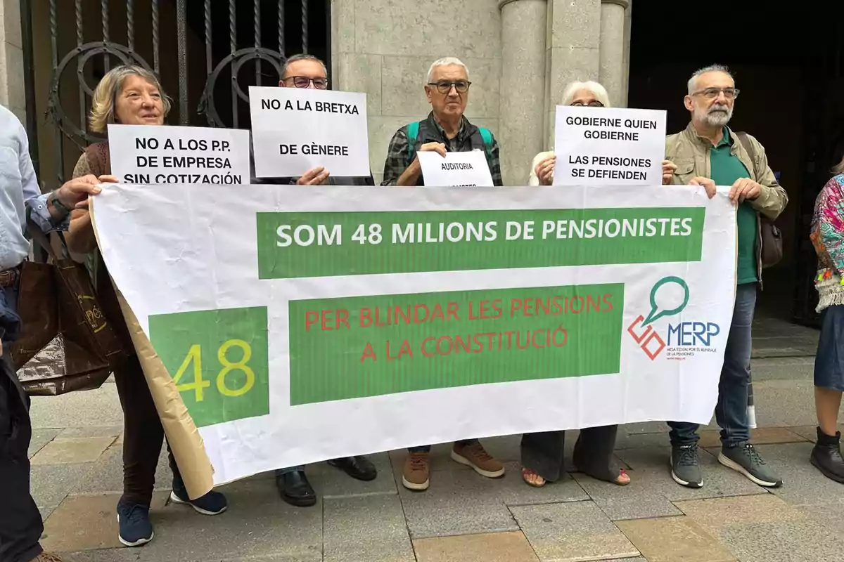 Un grup de persones sosté pancartes en una manifestació a favor de la protecció de les pensions a la constitució.