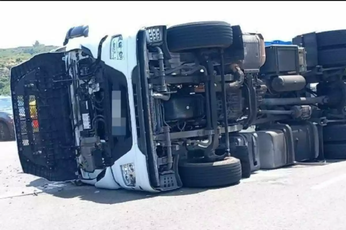 Camió de càrrega bolcat de costat en una carretera asfaltada durant el dia