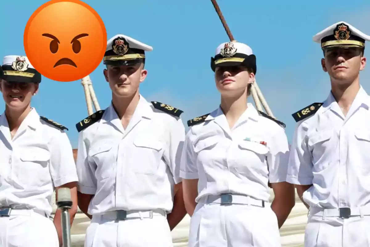Quatre persones amb uniforme naval blanc posen sota el sol i un emoji de cara enfadada cobreix parcialment una d’elles.