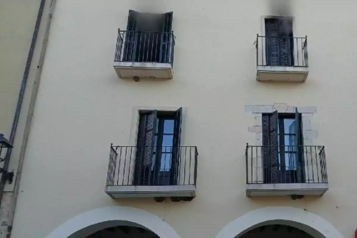 Façana d’edifici amb quatre balcons petits, dos d’ells amb marques de fum a la part superior de les finestres