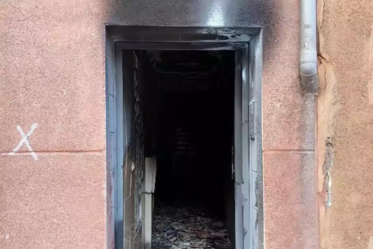 Porta d’edifici amb marques d’incendi i runa a l’interior