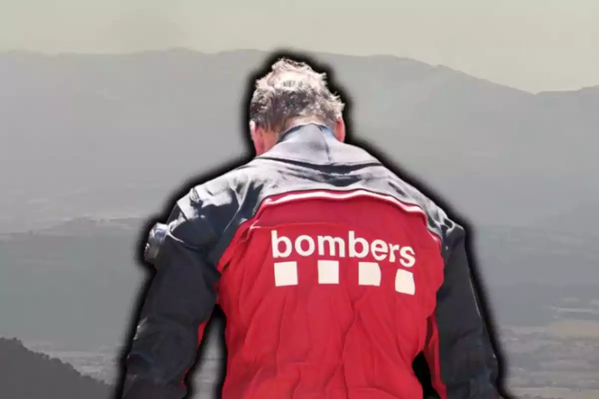 Persona d’esquena amb jaqueta vermella de bomber i paisatge de muntanyes al fons
