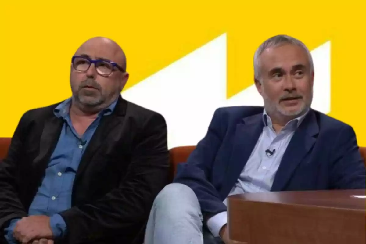 Dos hombres sentados en un set de televisión con fondo amarillo y blanco, ambos llevan saco y camisa, uno de ellos usa gafas azules.