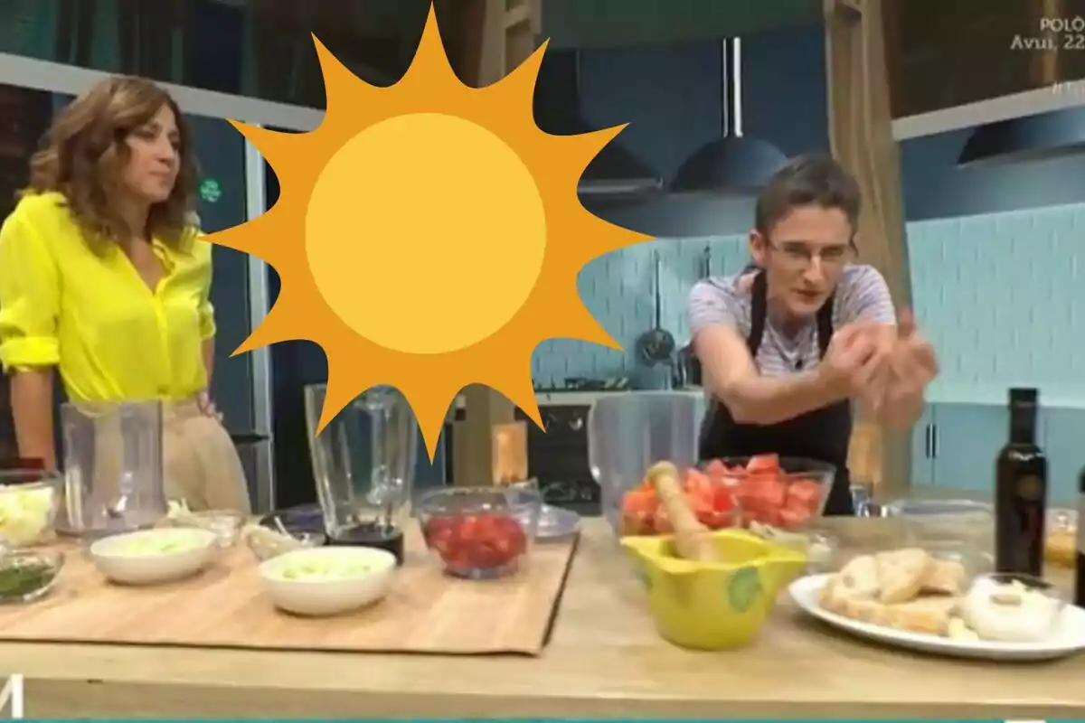 Dues persones en una cuina amb ingredients sobre la taula i un sol groc gran cobrint part de la imatge
