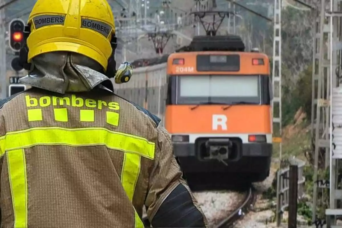Bombarder amb casc groc d’esquena davant d’un tren taronja aturat a les vies