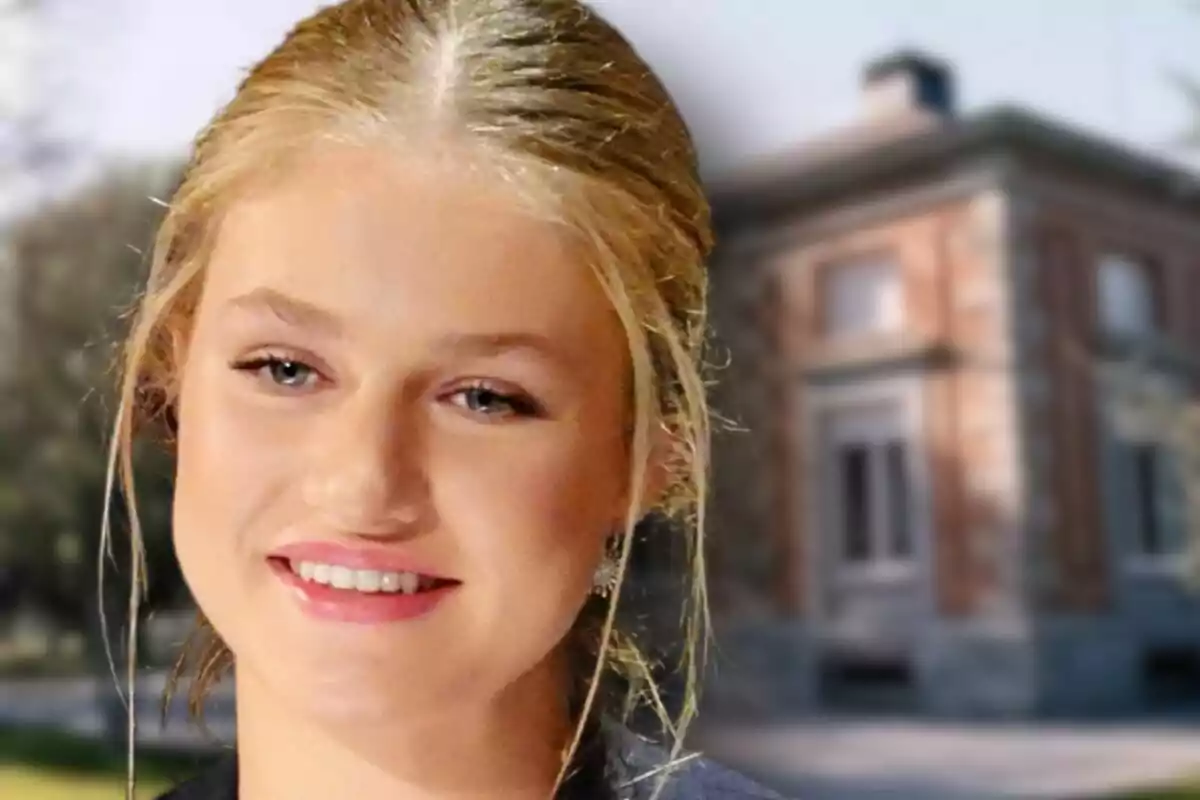 Close-up of Princess Leonor smiling with her hair tied back in front of a blurred brick building, which is the Zarzuela Palace.