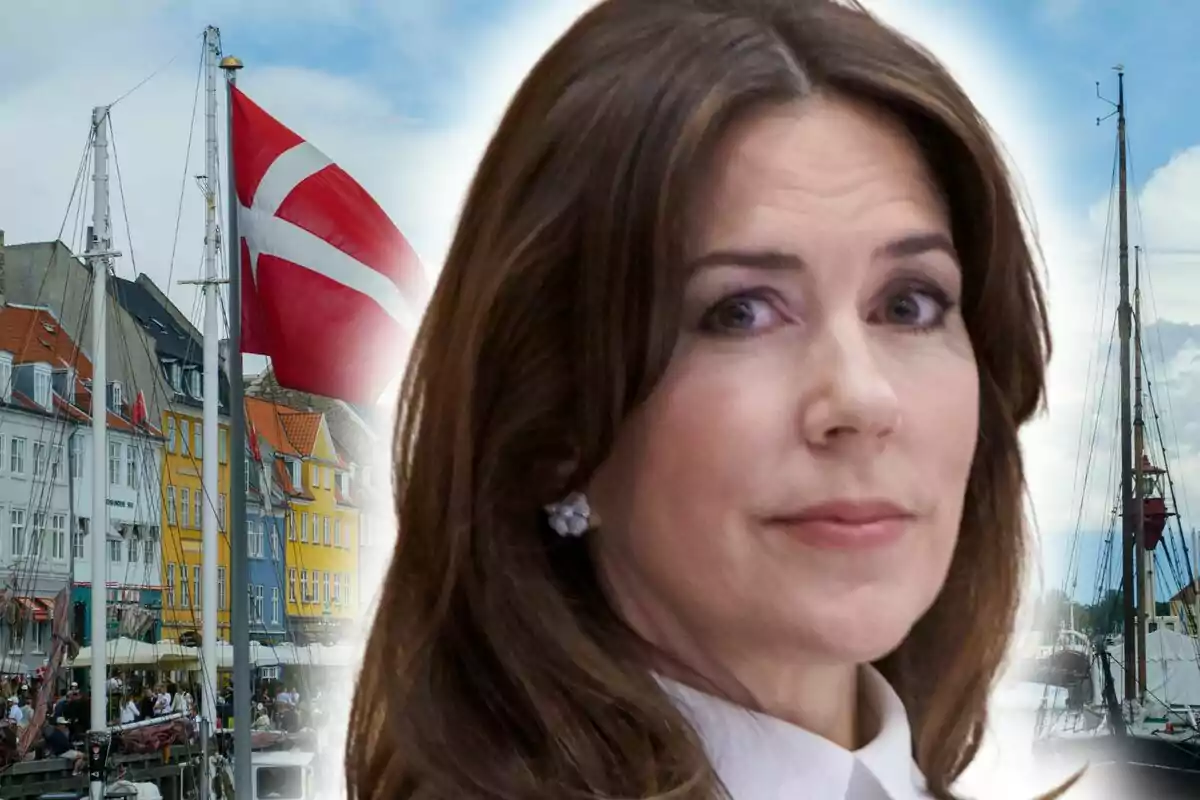 La reina María de Dinamarca en primer pla amb un fons de cases de colors, vaixells i una bandera de Dinamarca onejant.