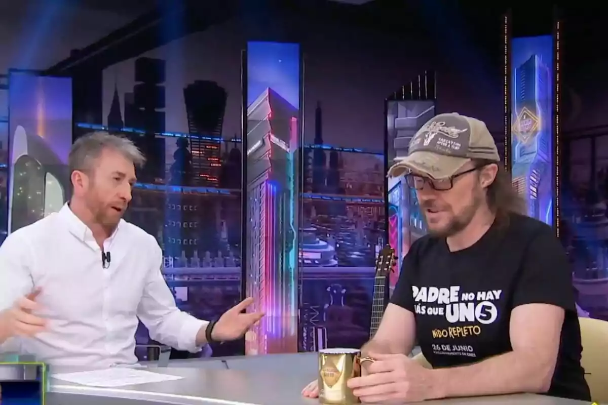Pablo Motos y Santiago Segura conversan en 'El Hormiguero', uno lleva camisa blanca y el otro camiseta negra y gorra, ambos sentados en una mesa con tazas doradas. Pablo Motos y Santiago Segura conversan en 'El Hormiguero', uno lleva camisa blanca y el otro camiseta negra y gorra, ambos sentados en una mesa con tazas doradas.