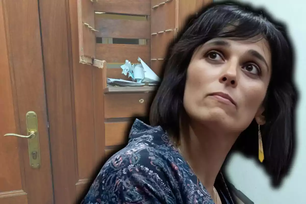 Dona de cabells foscos amb expressió seriosa en primer pla i al fons una porta i un moble de fusta malmesos amb papers desordenats.