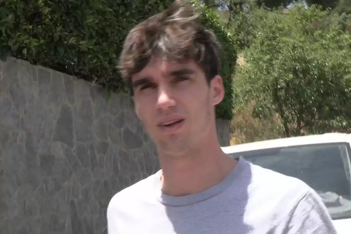 Pablo Urdangarin con camiseta gris caminando al aire libre junto a un muro de piedra y vegetación Pablo Urdangarin con camiseta gris caminando al aire libre junto a un muro de piedra y vegetación