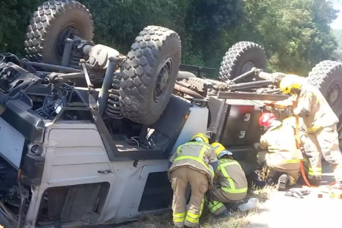 Bombers treballen en el rescat després del bolcament d’un vehicle militar en una zona boscosa