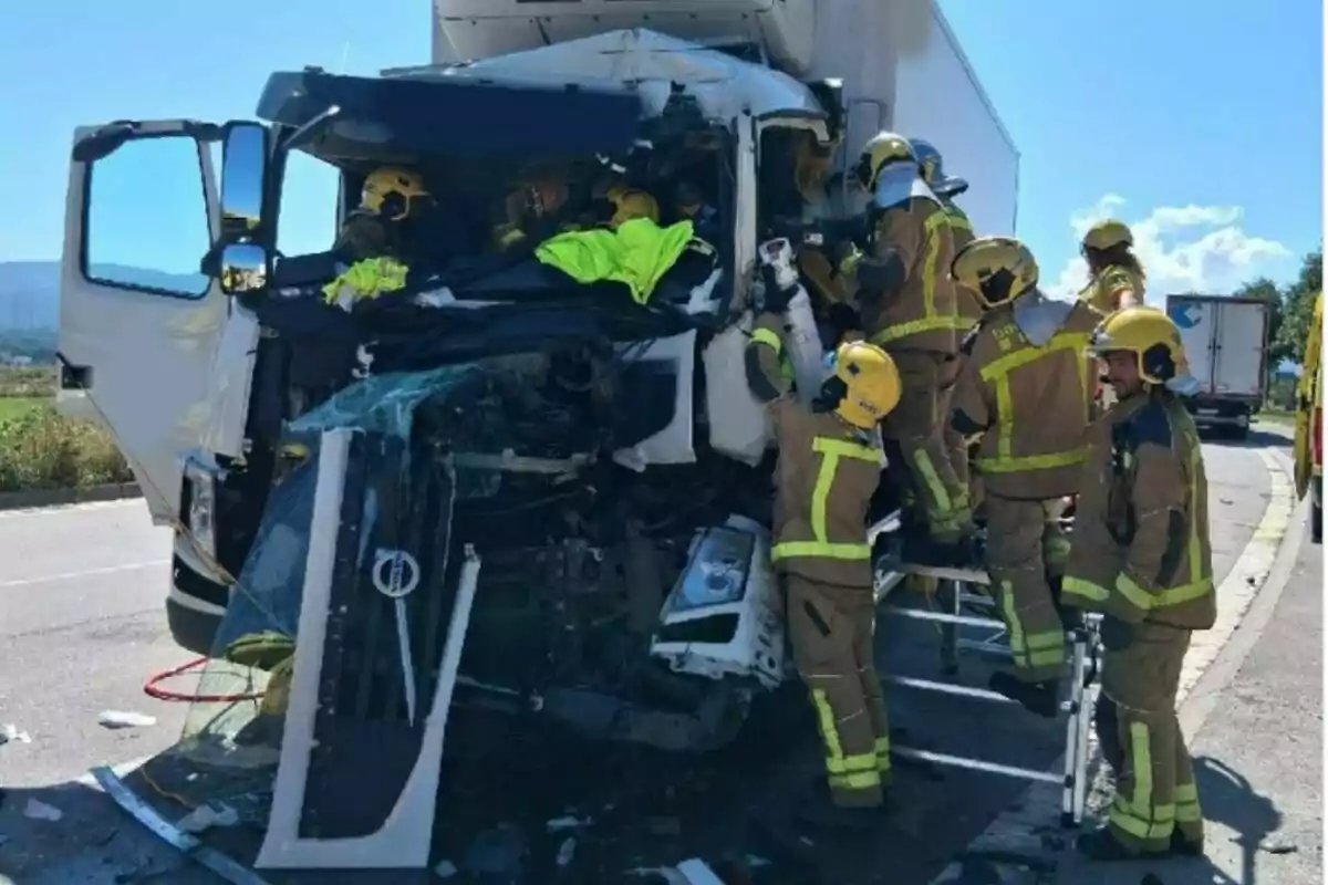 Diversos bombers treballen en el rescat de persones atrapades a la cabina destrossada d’un camió després d’un accident a la carretera.