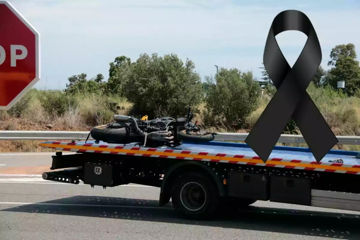 Grua transportant una motocicleta accidentada amb un llaç negre de dol sobre la imatge