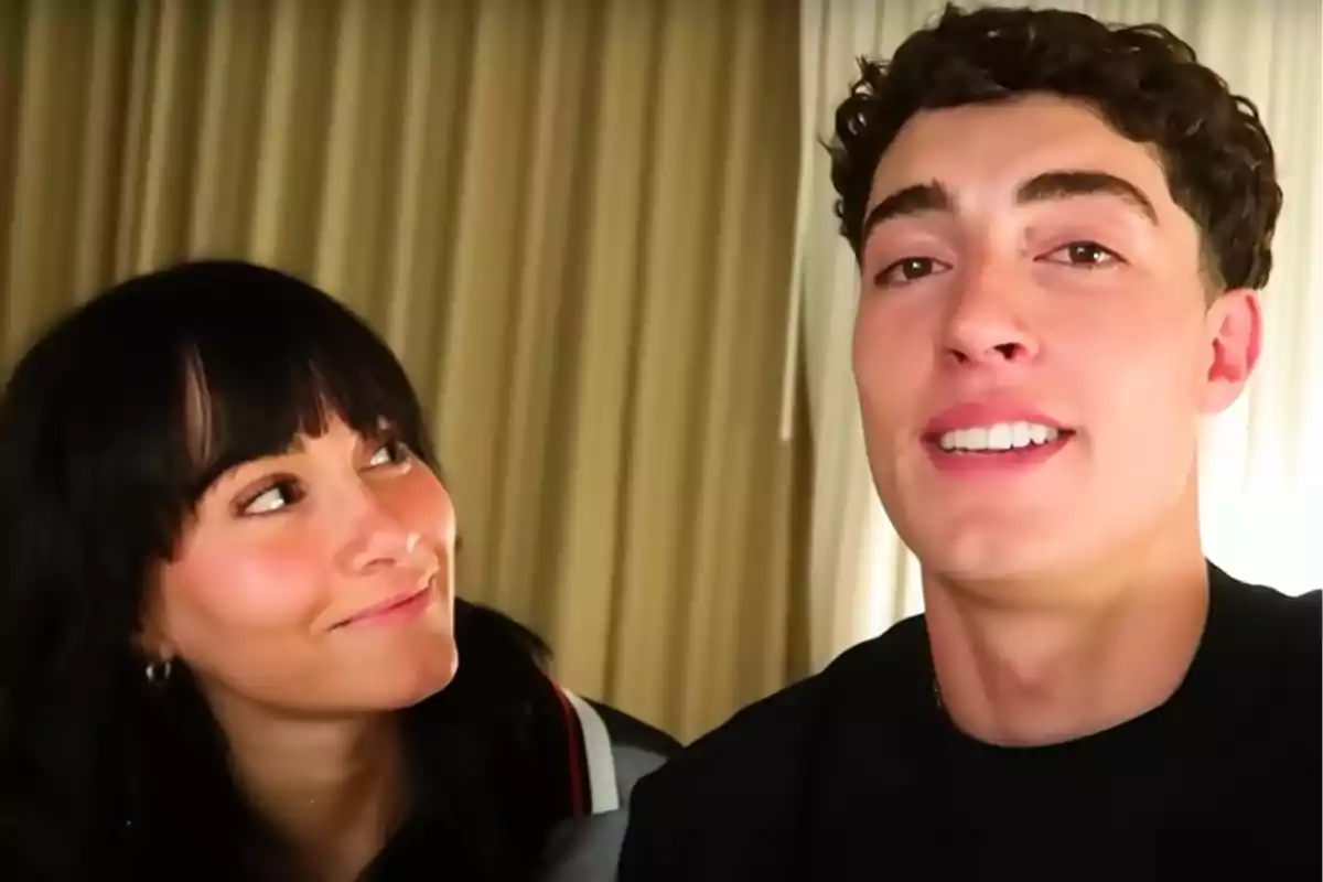Aitana mira somrient a Plex, que està somrient davant de la càmera, amb cortines beix de fons. Aitana mira somrient a Plex, que està somrient davant de la càmera, amb cortines beix de fons.
