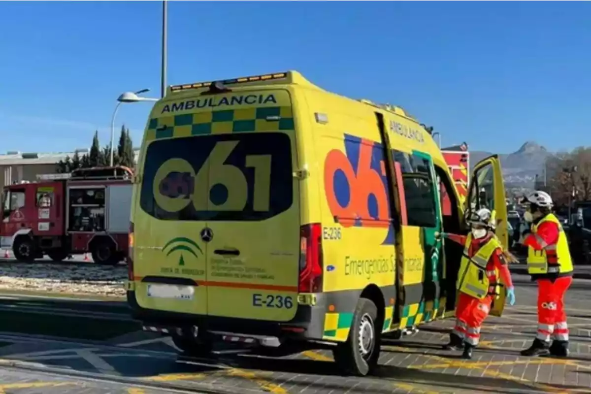Ambulància groga del servei d’emergències 061 d’Andalusia estacionada al costat d’un camió de bombers amb dos sanitaris vestits amb armilles reflectants i uniforme vermell Ambulància groga del servei d’emergències 061 d’Andalusia estacionada al costat d’un camió de bombers amb dos sanitaris vestits amb armilles reflectants i uniforme vermell