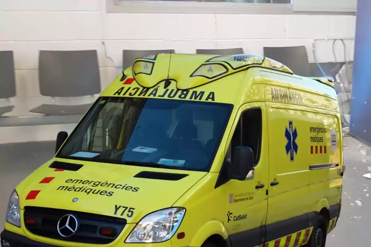 Ambulància groga d’emergències mèdiques estacionada davant d’una sala d’espera amb cadires grises