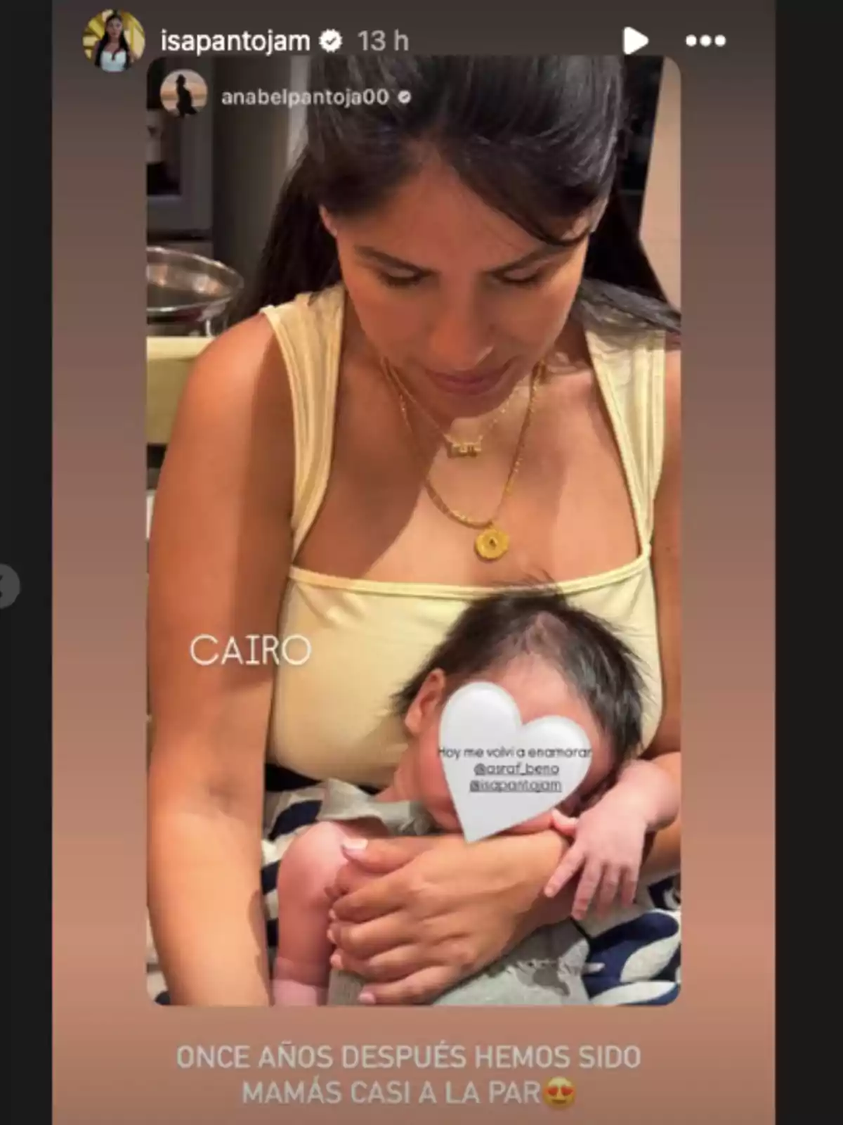 Isa Pantoja amb cabell fosc sosté en braços un nadó la cara del qual està coberta per un cor blanc amb text, tots dos estan asseguts i la dona porta un top beix i collarets daurats, el fons és interior i la imatge té un filtre càlid. Isa Pantoja amb cabell fosc sosté en braços un nadó la cara del qual està coberta per un cor blanc amb text, tots dos estan asseguts i la dona porta un top beix i collarets daurats, el fons és interior i la imatge té un filtre càlid.