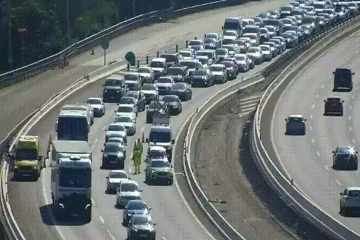 Tráfico denso en una autopista con varios carriles bloqueados y vehículos detenidos mientras algunos autos circulan libremente en el sentido contrario