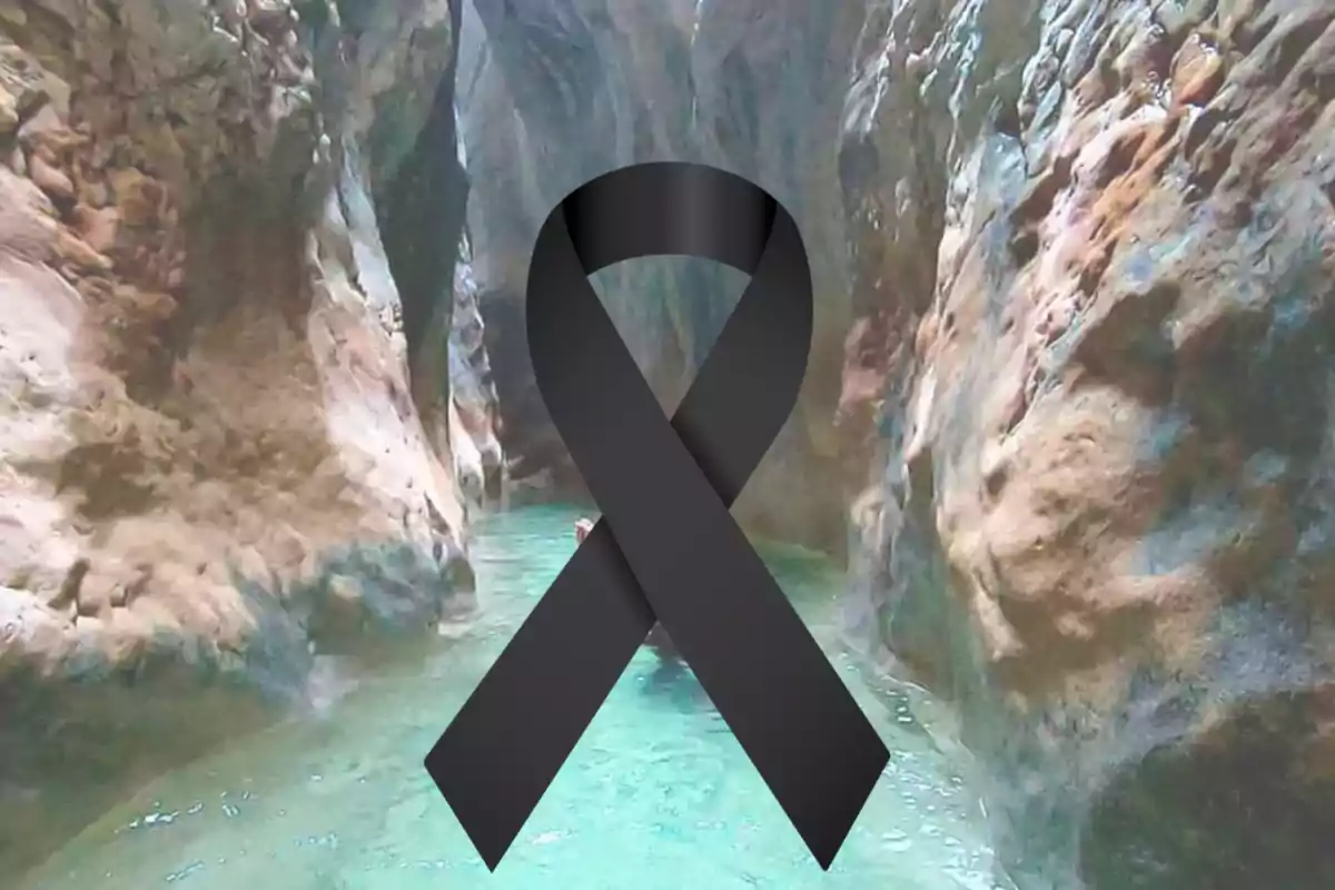 Canyó de parets rocoses amb aigua turquesa i un llaç negre de dol al centre