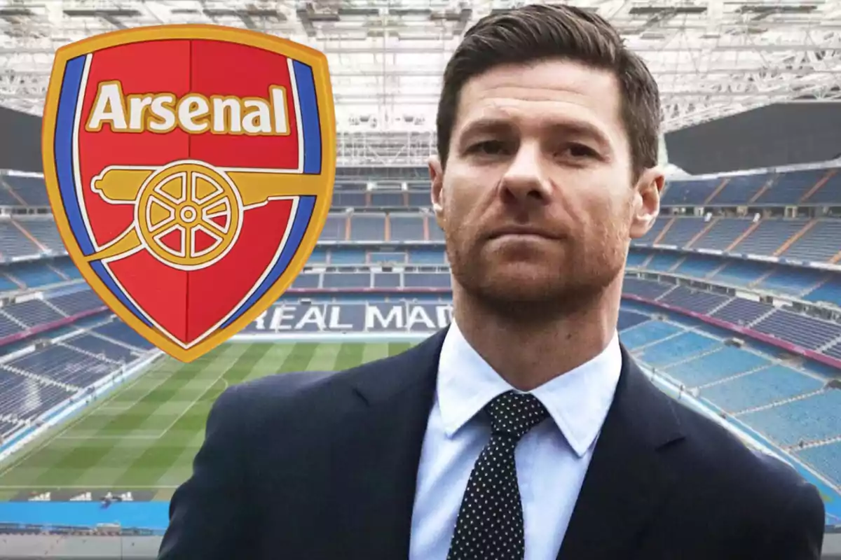 Hombre con traje en un estadio de fútbol con el escudo del Arsenal a la izquierda