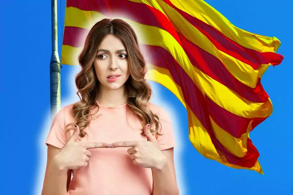 Dona amb expressió de dubte assenyalant-se a si mateixa davant d’una bandera amb franges vermelles i grogues onejant sobre un cel blau