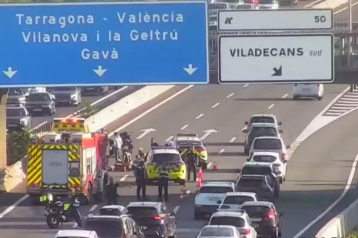 Diversos vehicles d’emergència i policies atenen un incident en una autopista a prop d’una sortida cap a Viladecans mentre el trànsit es troba aturat
