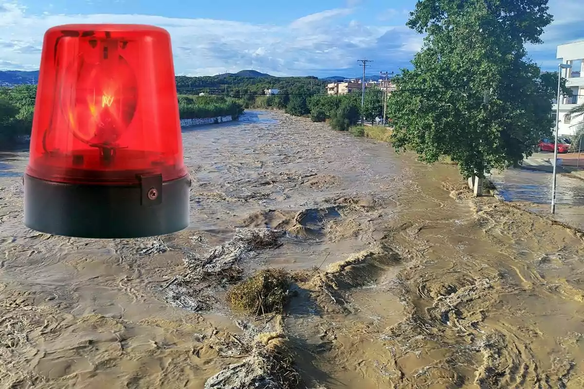 Alerta d’inundació amb un riu desbordat i una sirena vermella superposada a la imatge Alerta d’inundació amb un riu desbordat i una sirena vermella superposada a la imatge