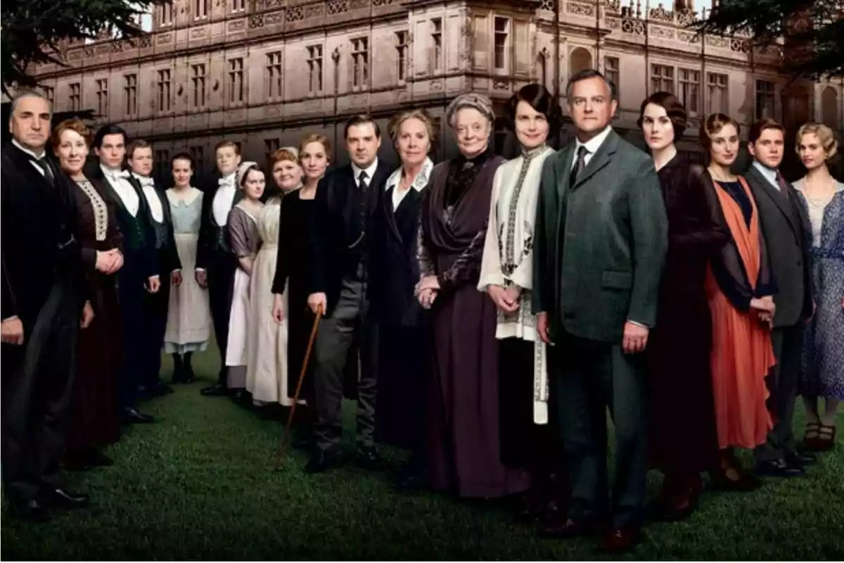 Elenco de una serie de época posando frente a una mansión elegante Elenco de una serie de época posando frente a una mansión elegante