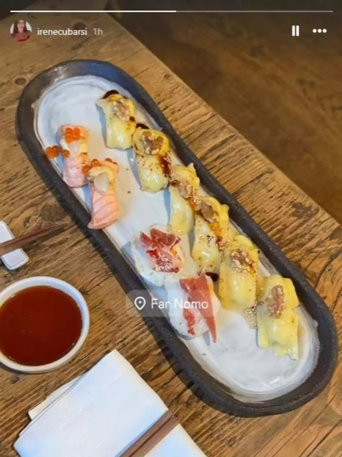 Safata de sushi variat sobre una taula de fusta al costat d’un petit bol de salsa i uns bastonets Safata de sushi variat sobre una taula de fusta al costat d’un petit bol de salsa i uns bastonets
