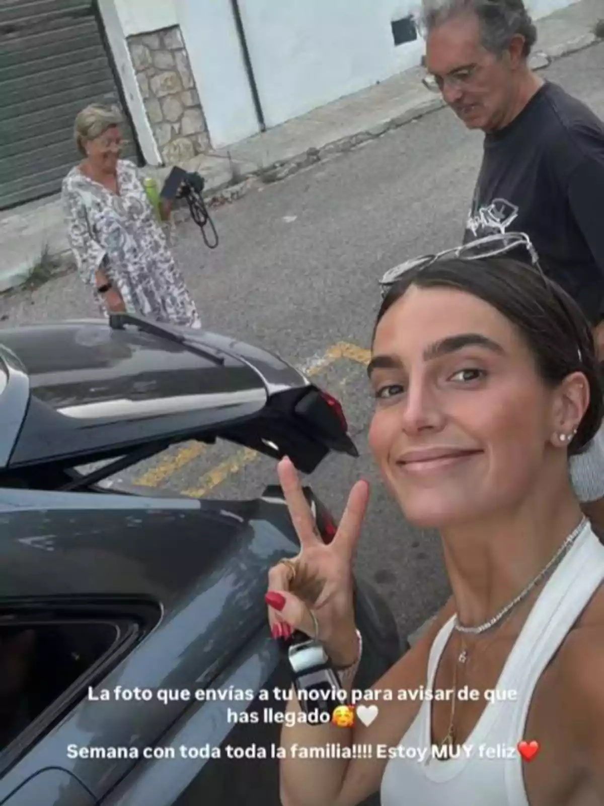 Una jove somrient es fa una selfie mostrant el signe de la pau al costat d’un cotxe gris, mentre al fons es veuen dues persones grans, un home i una dona, en un carrer; sobre la imatge hi ha un text que expressa felicitat per estar amb la família. Una jove somrient es fa una selfie mostrant el signe de la pau al costat d’un cotxe gris, mentre al fons es veuen dues persones grans, un home i una dona, en un carrer; sobre la imatge hi ha un text que expressa felicitat per estar amb la família.