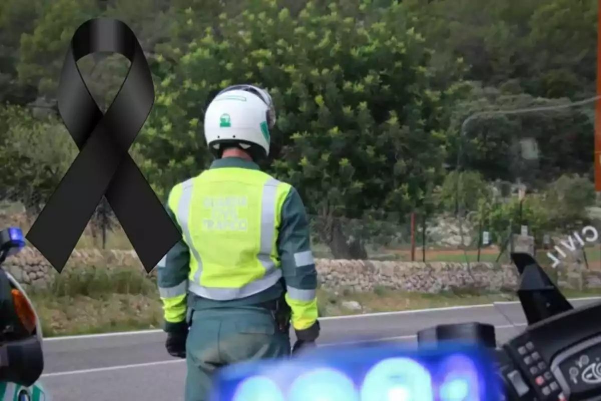 Agent de la Guàrdia Civil de Trànsit d’esquena en una carretera al costat d’un llaç negre de dol