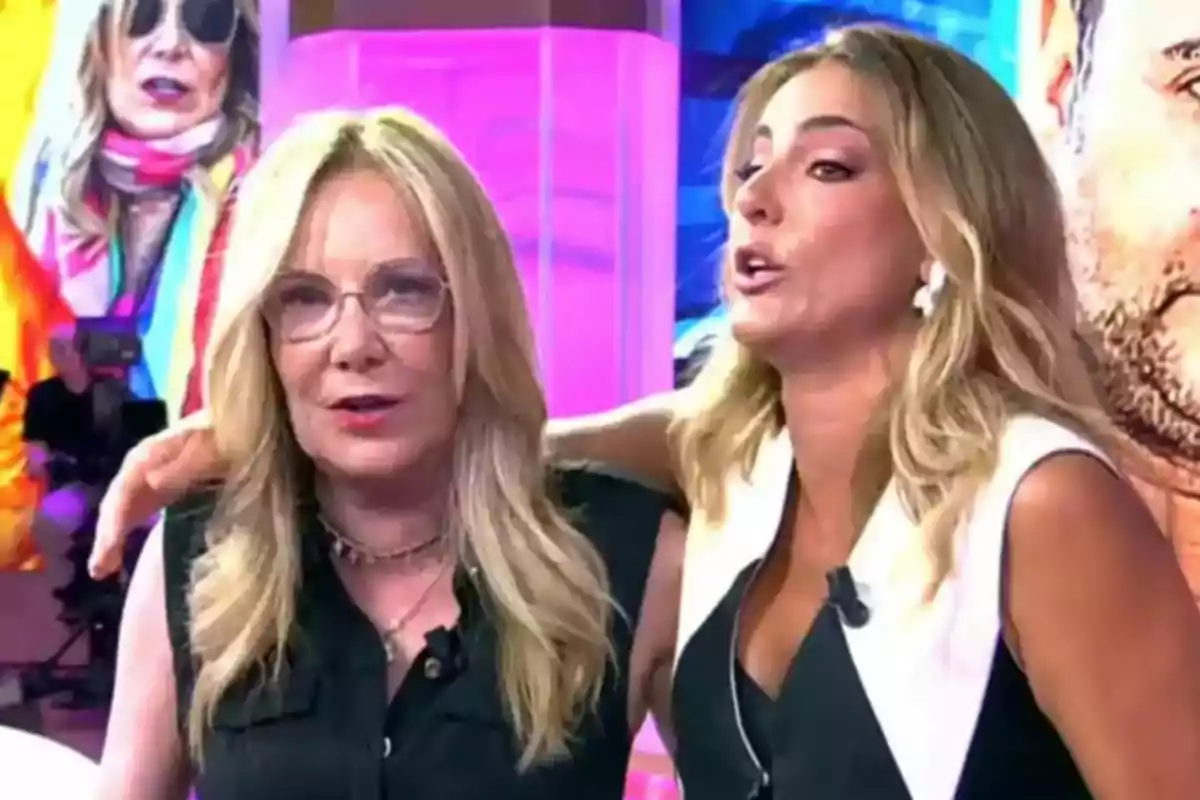 Dues dones rosses són en un plató de televisió, una d’elles porta ulleres i ambdues semblen estar conversant animadament mentre una abraça l’altra. Dues dones rosses són en un plató de televisió, una d’elles porta ulleres i ambdues semblen estar conversant animadament mentre una abraça l’altra.