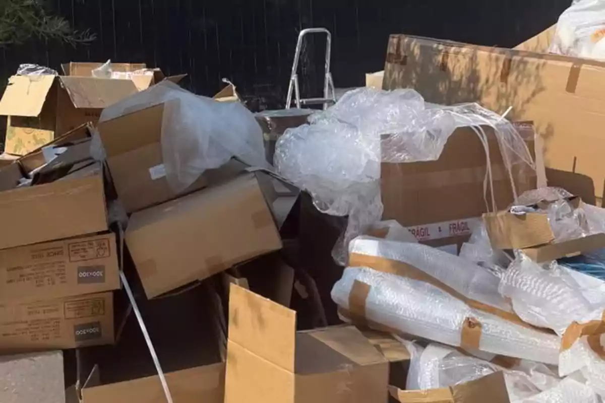 Montón de cajas de cartón y plástico de embalaje apilados en el exterior junto a una escalera Montón de cajas de cartón y plástico de embalaje apilados en el exterior junto a una escalera