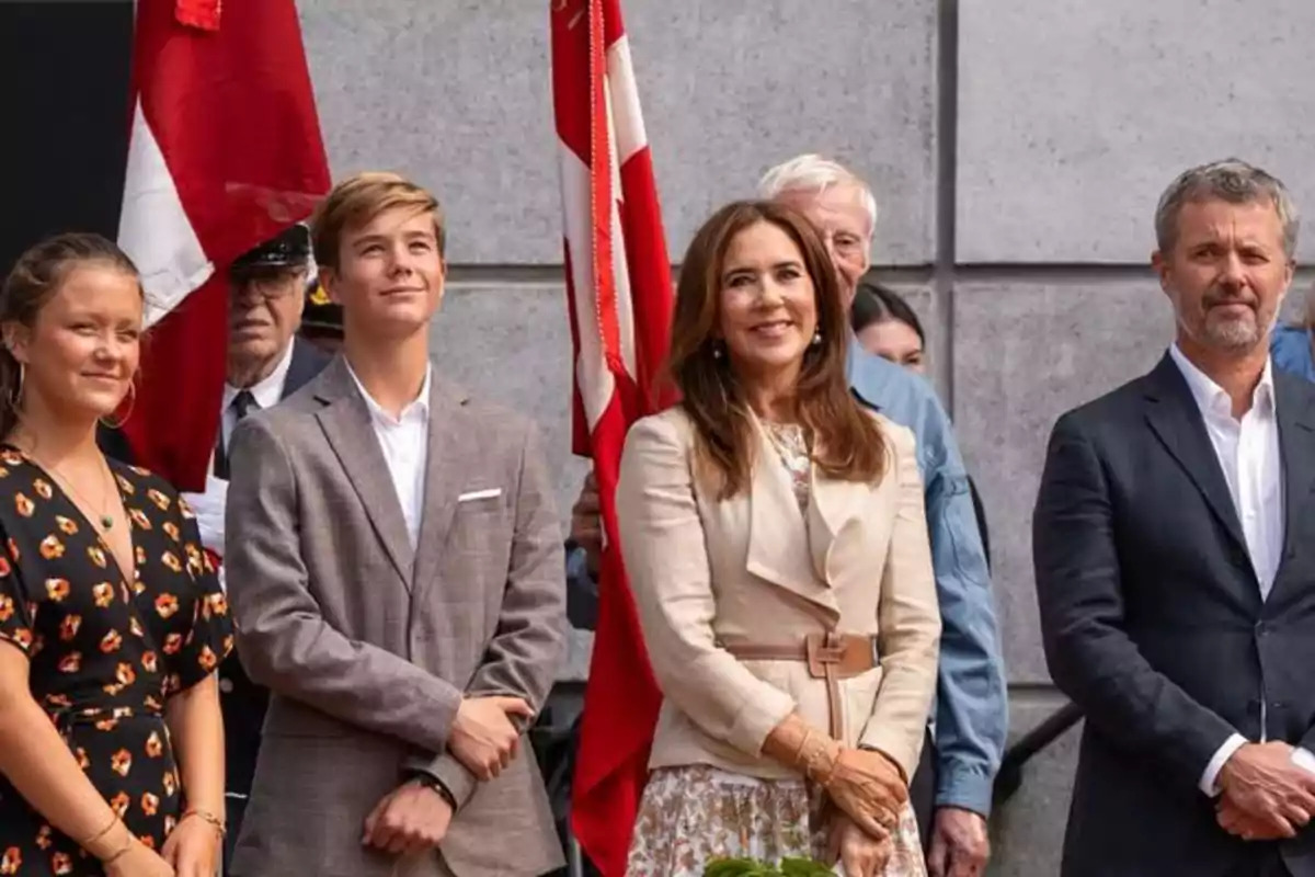 La Familia Real de Dinamarca bien vestidos posando al aire libre frente a una bandera roja y blanca La Familia Real de Dinamarca bien vestidos posando al aire libre frente a una bandera roja y blanca
