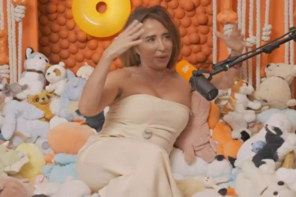 María Patiño sentada rodeada de peluches en un ambiente decorado en tonos naranjas mientras habla frente a un micrófono María Patiño sentada rodeada de peluches en un ambiente decorado en tonos naranjas mientras habla frente a un micrófono