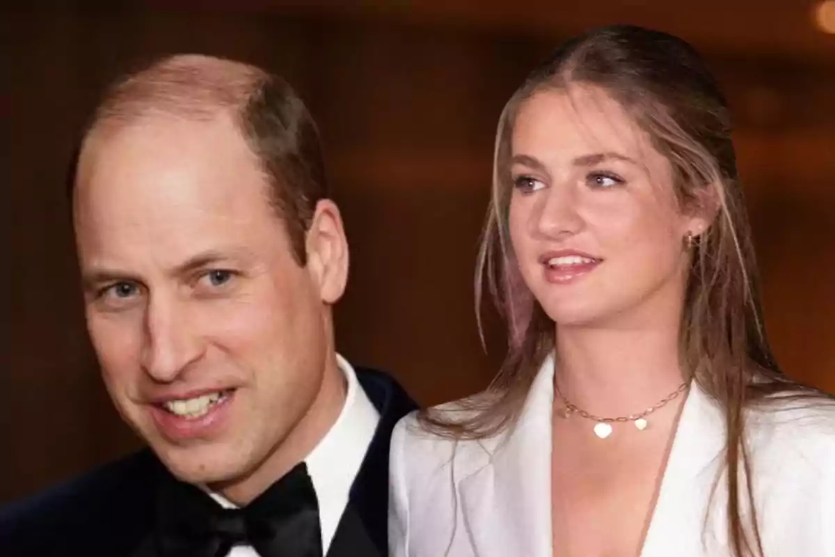 El principe Guillermo con esmoquin y la princesa Leonor joven con chaqueta blanca posan juntos frente a un fondo marrón desenfocado