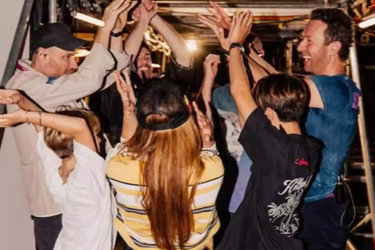 Un grup de persones formant un cercle i aixecant els braços mentre somriuen i celebren junts Un grup de persones formant un cercle i aixecant els braços mentre somriuen i celebren junts