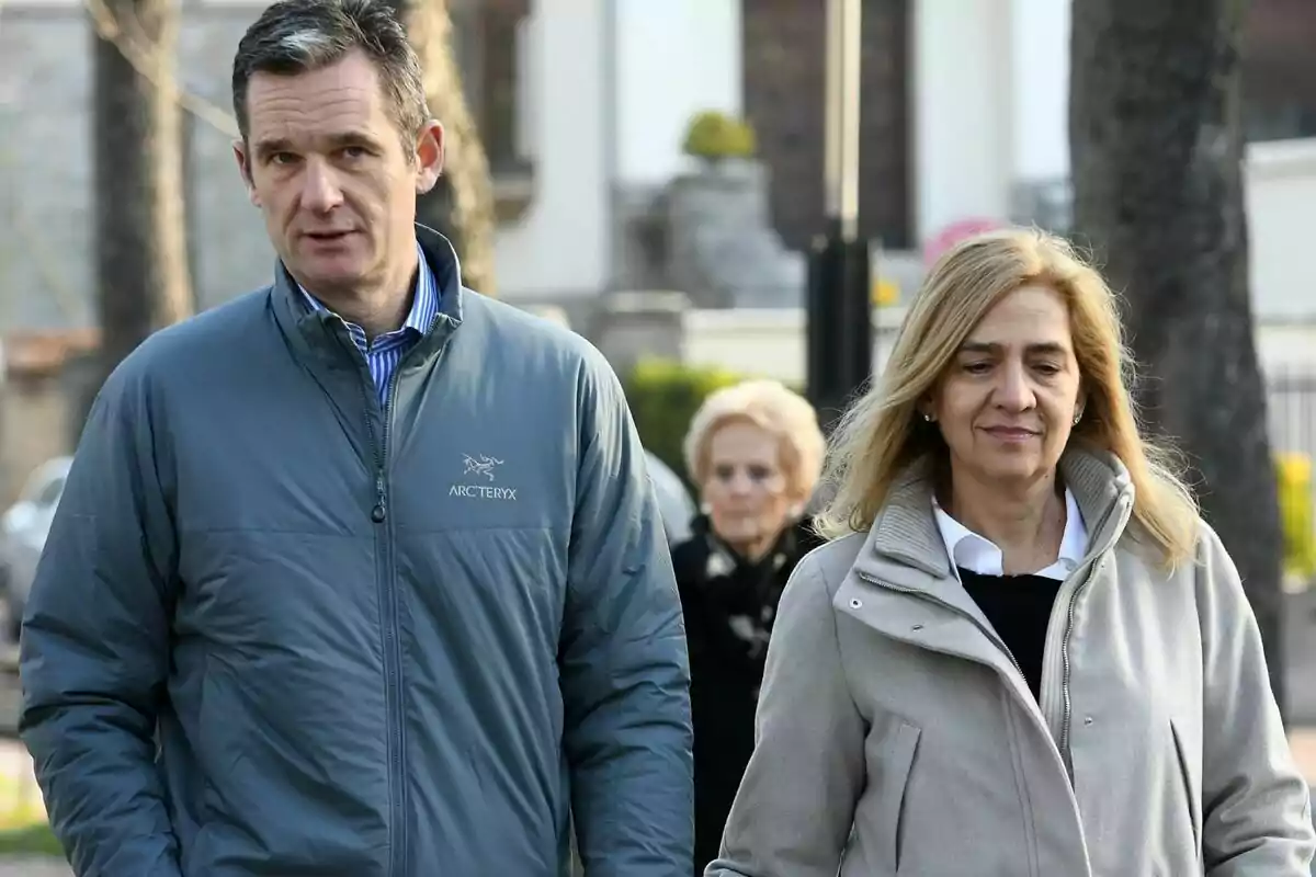 La Infanta Cristina e Iñaki Urdangarín, en una imagen de archivo, caminando juntos al aire libre con una persona mayor al fondo en un entorno urbano. La Infanta Cristina e Iñaki Urdangarín, en una imagen de archivo, caminando juntos al aire libre con una persona mayor al fondo en un entorno urbano.