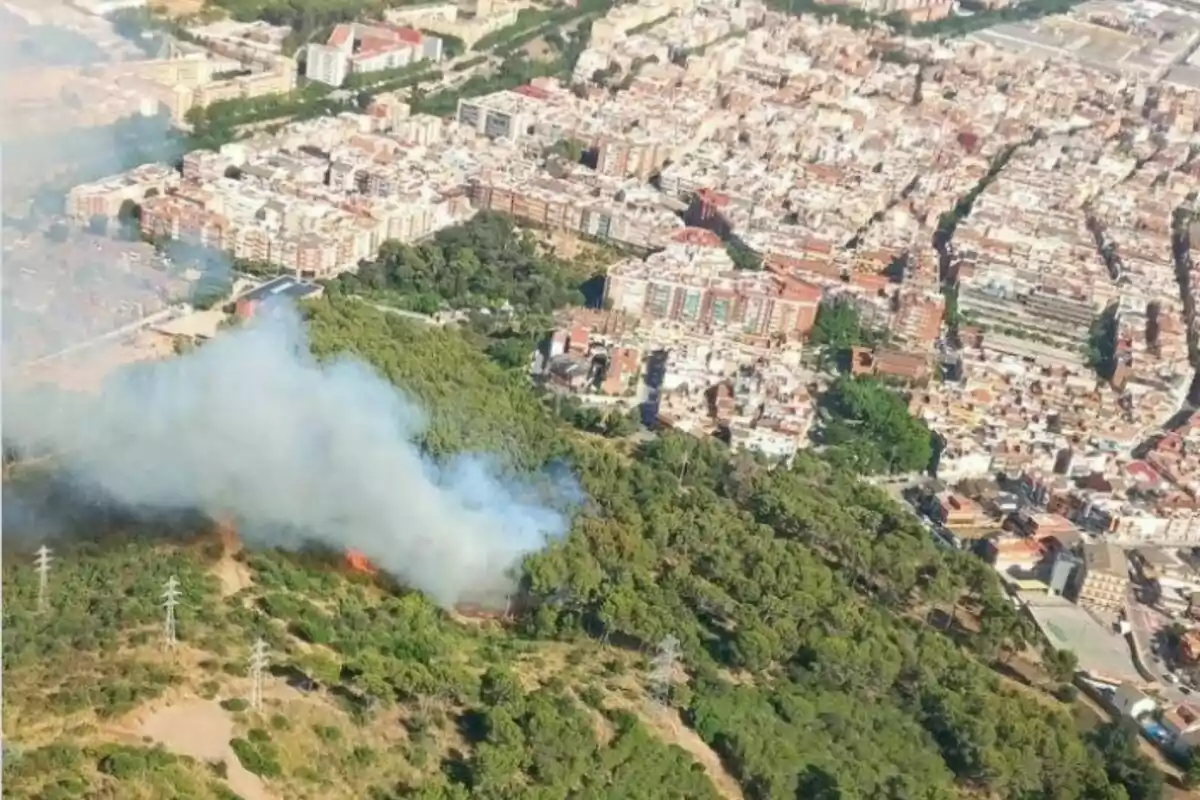 Vista aèria d’un incendi forestal en una zona boscosa propera a una ciutat
