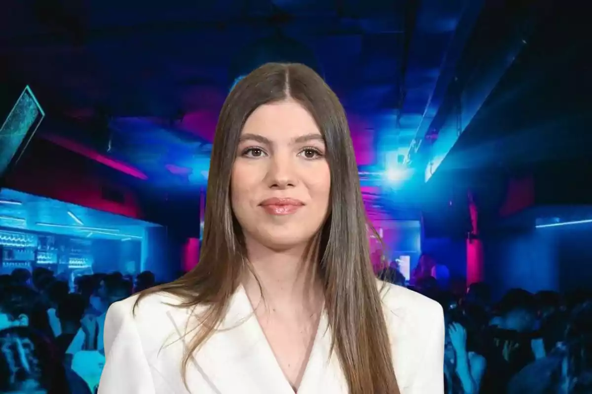 La infanta Sofía de cabello lacio y castaño con saco blanco posando frente a un fondo de club nocturno iluminado con luces azules y rosas