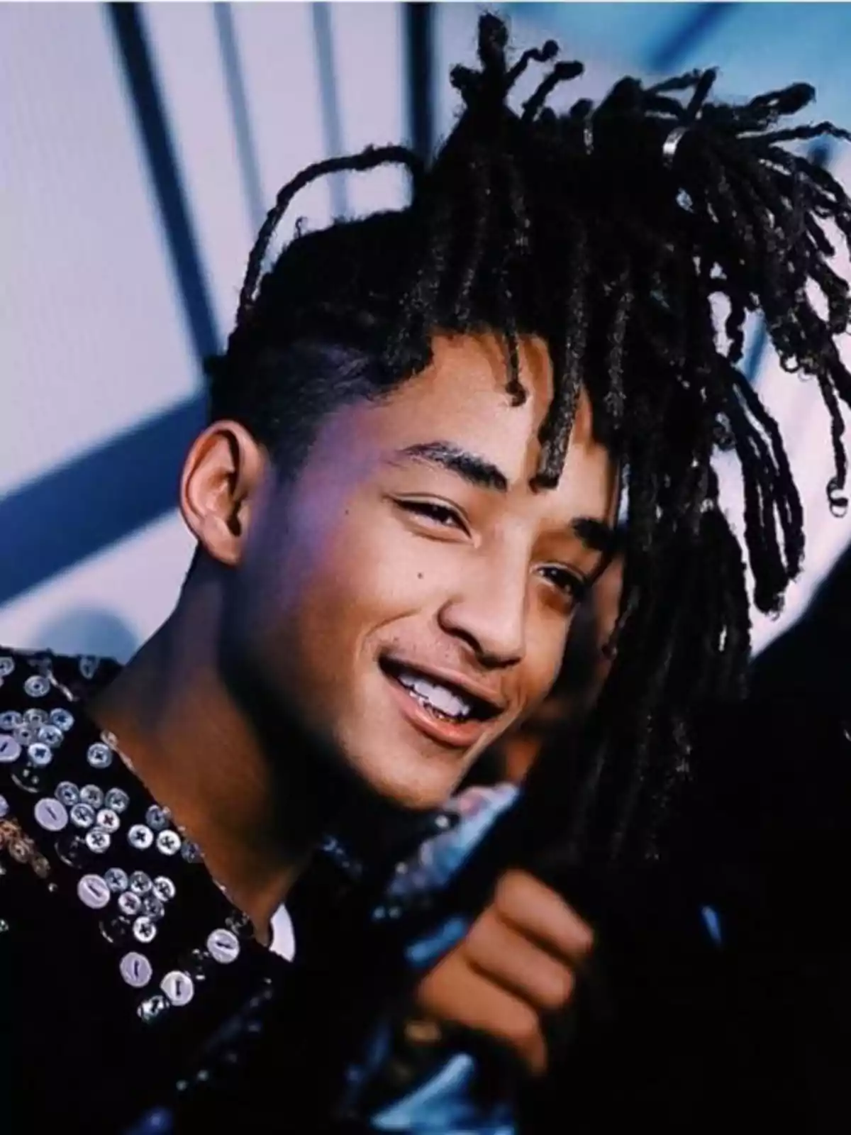 Jaden Smith amb rastes llargues i jersei decorat amb botons somriu mentre mira cap a la càmera Jaden Smith amb rastes llargues i jersei decorat amb botons somriu mentre mira cap a la càmera