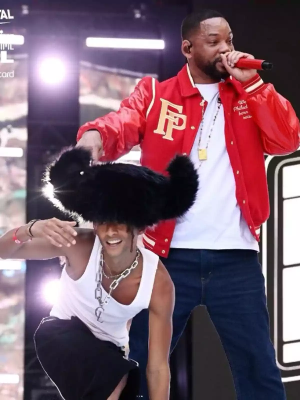 Will Smith i Jaden Smith a l’escenari durant un concert, una d’elles porta una jaqueta vermella i canta amb un micròfon mentre l’altra porta un barret gran i negre. Will Smith i Jaden Smith a l’escenari durant un concert, una d’elles porta una jaqueta vermella i canta amb un micròfon mentre l’altra porta un barret gran i negre.