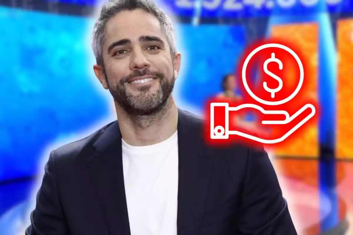 Hombre sonriente con barba y cabello corto, vistiendo camiseta blanca y saco oscuro, al fondo un escenario colorido y un gráfico de mano con símbolo de dinero. Hombre sonriente con barba y cabello corto, vistiendo camiseta blanca y saco oscuro, al fondo un escenario colorido y un gráfico de mano con símbolo de dinero.