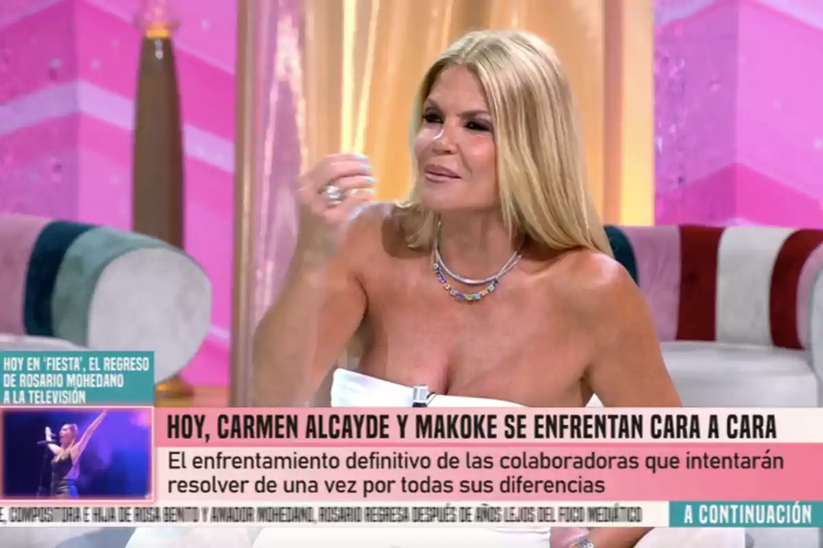 Makoke asseguda en un plató de televisió amb un fons rosa i daurat, parlant i gesticulant durant un programa on s’anuncia un enfrontament entre col·laboradores. Makoke asseguda en un plató de televisió amb un fons rosa i daurat, parlant i gesticulant durant un programa on s’anuncia un enfrontament entre col·laboradores.
