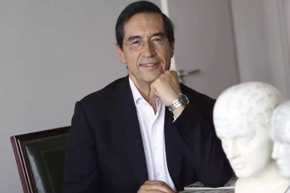 Mario Alonso Puig assegut en una oficina, recolzant la barbeta a la mà, amb bustos de models anatòmics en primer pla. Mario Alonso Puig assegut en una oficina, recolzant la barbeta a la mà, amb bustos de models anatòmics en primer pla.