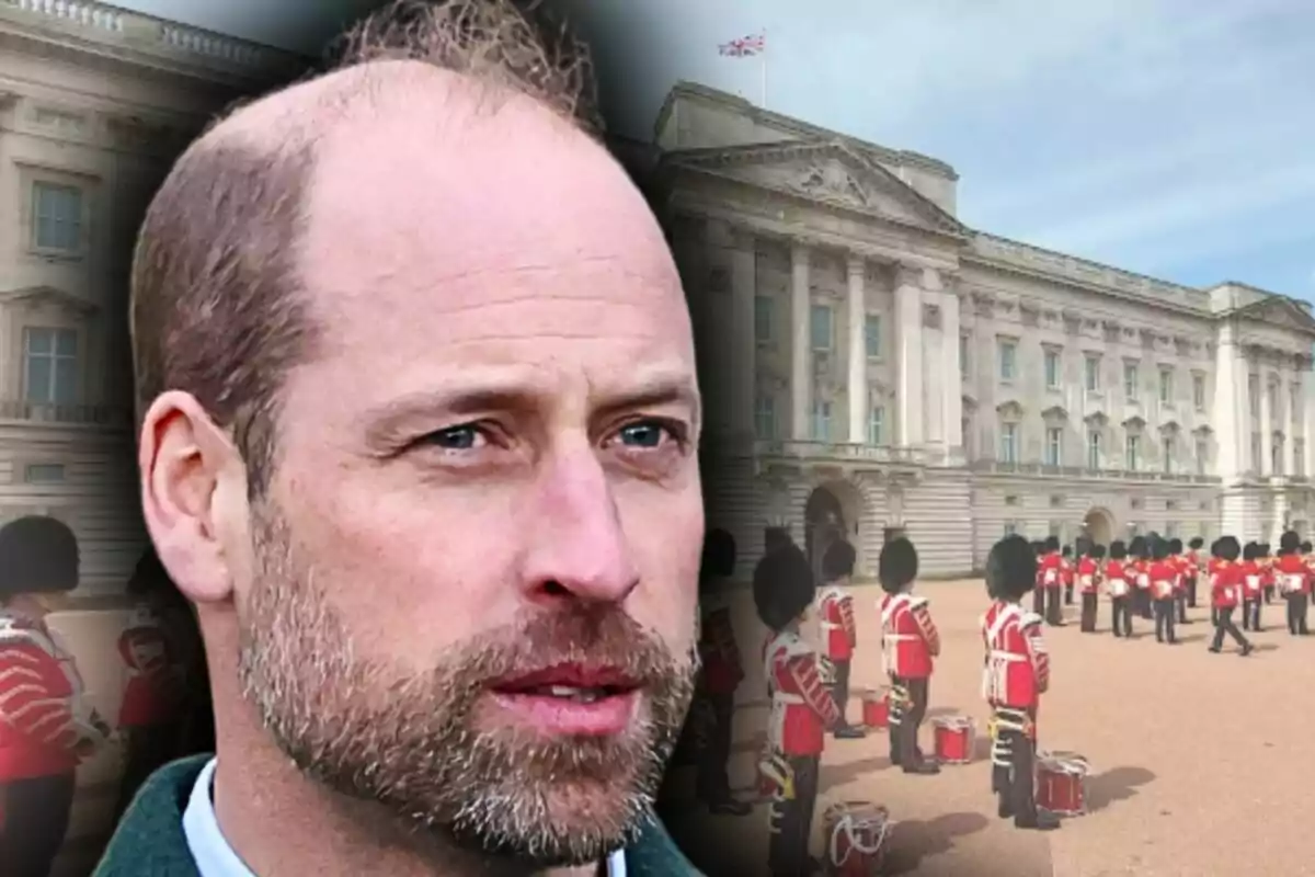Primer plano del príncipe Guillermo con el fondo difuminado del Palacio de Buckingham con guardias británicos uniformados.