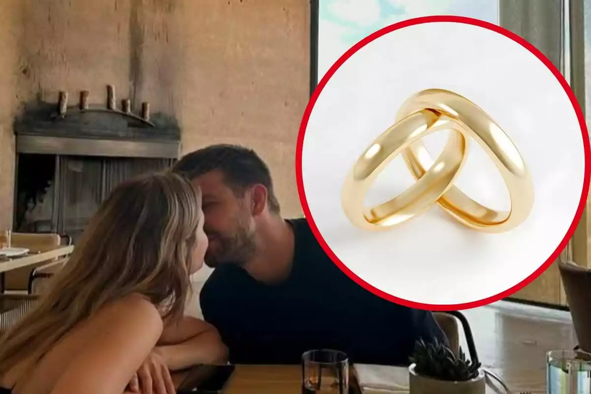 Parella asseguda en un restaurant apropant-se per fer-se un petó amb un cercle que mostra dos anells daurats entrellaçats