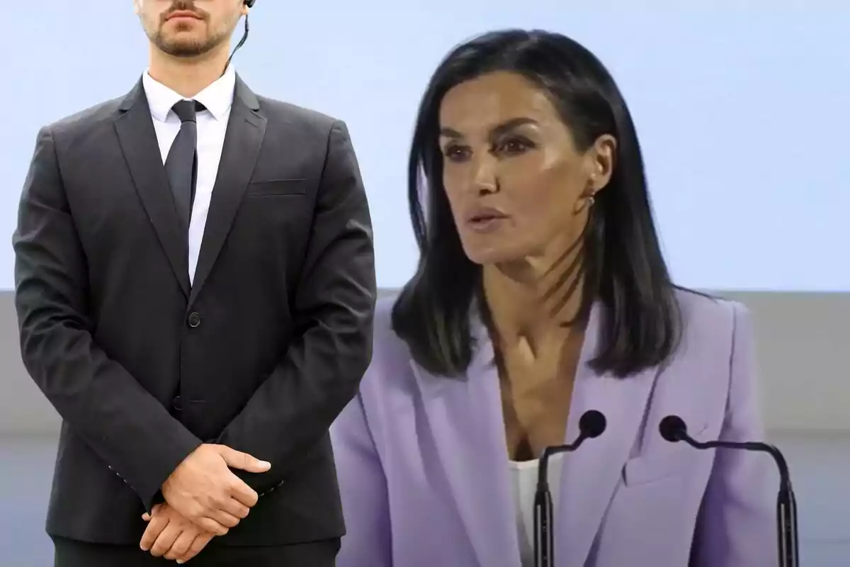 Mujer de cabello oscuro hablando en un podio mientras un hombre con traje negro y auricular de seguridad está de pie al lado