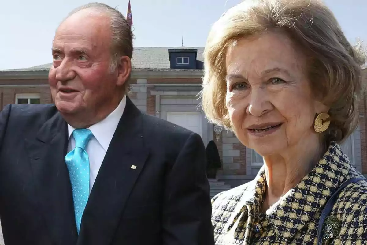 Un home amb vestit fosc i corbata blava al costat d’una dona gran amb jaqueta estampada i arracades daurades posen davant d’un edifici de maó.