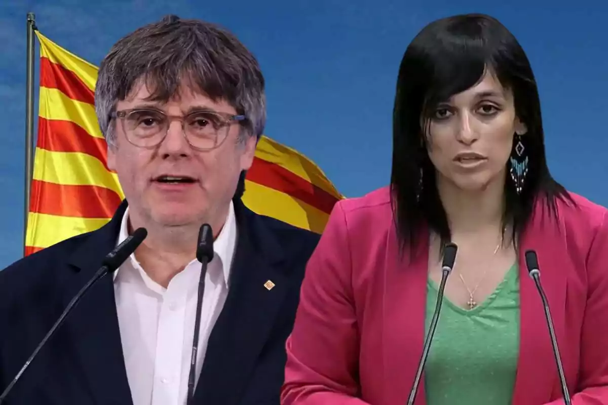 Dues persones parlant davant de micròfons amb una bandera catalana de fons i cel blau